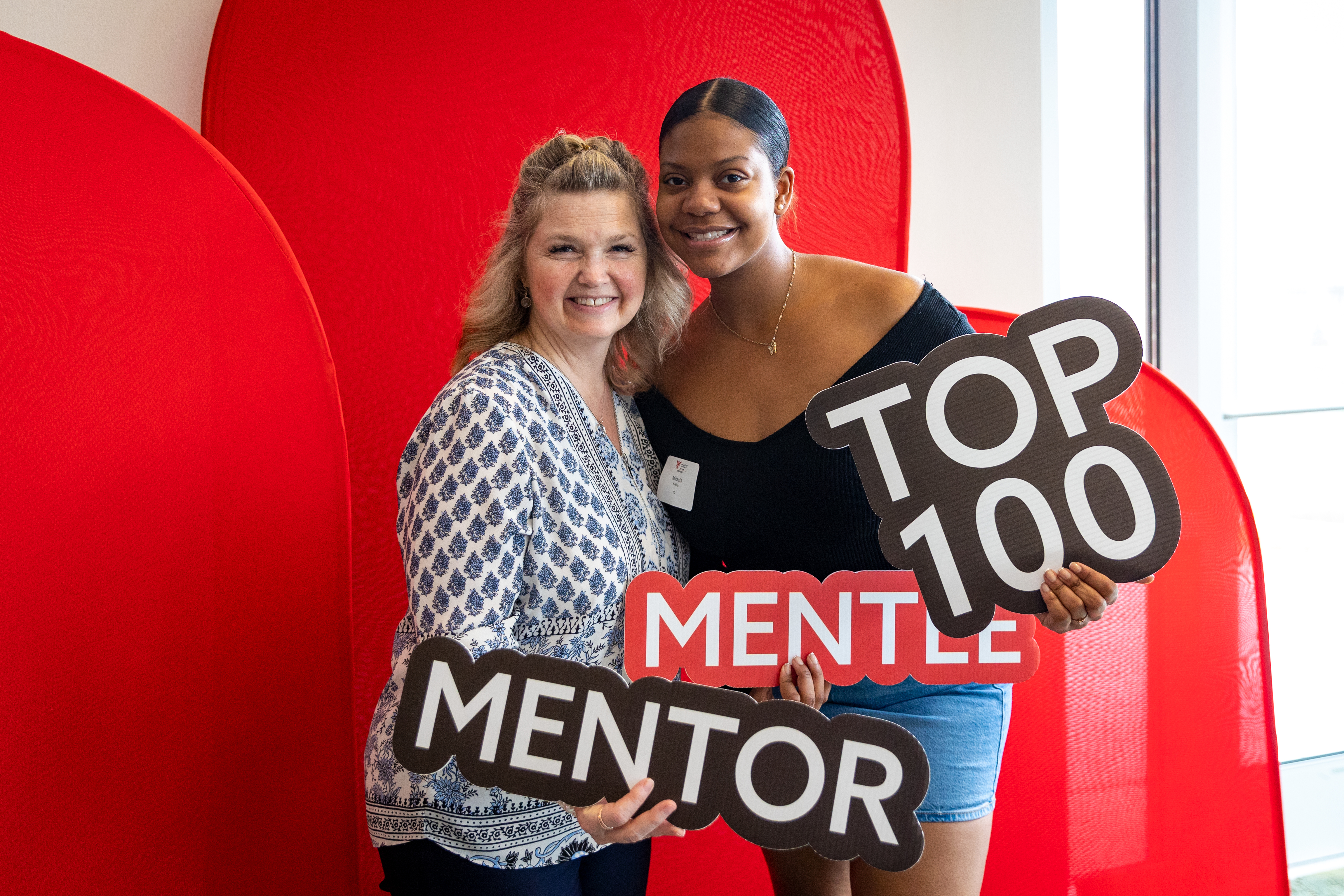 Two people holding mentor and mentoring signs