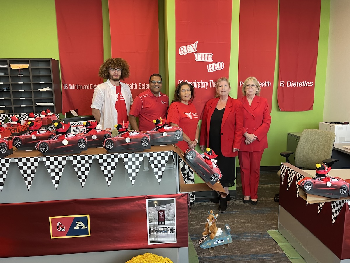 People in Red and White attire behind desk with race theme decor