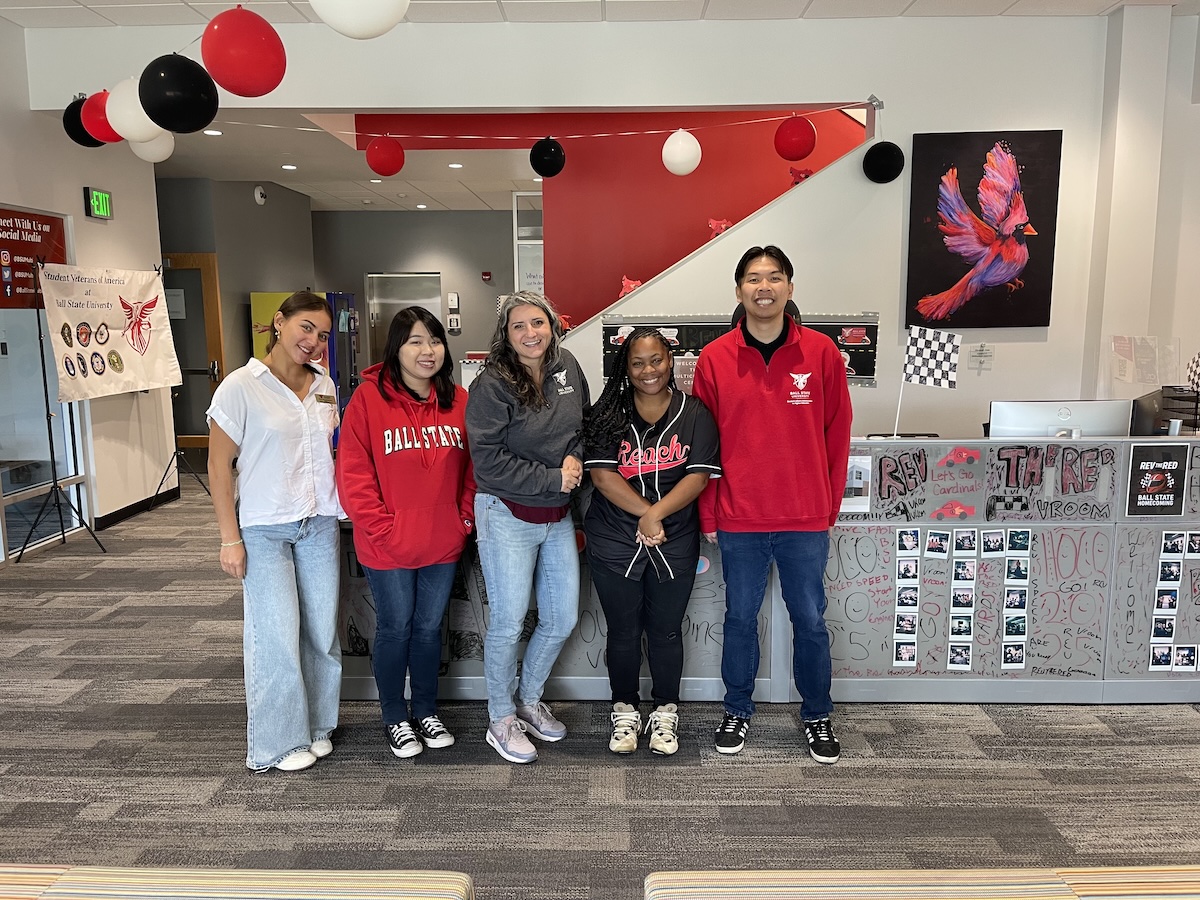People in front of decorate desk/wall with red and white balloons