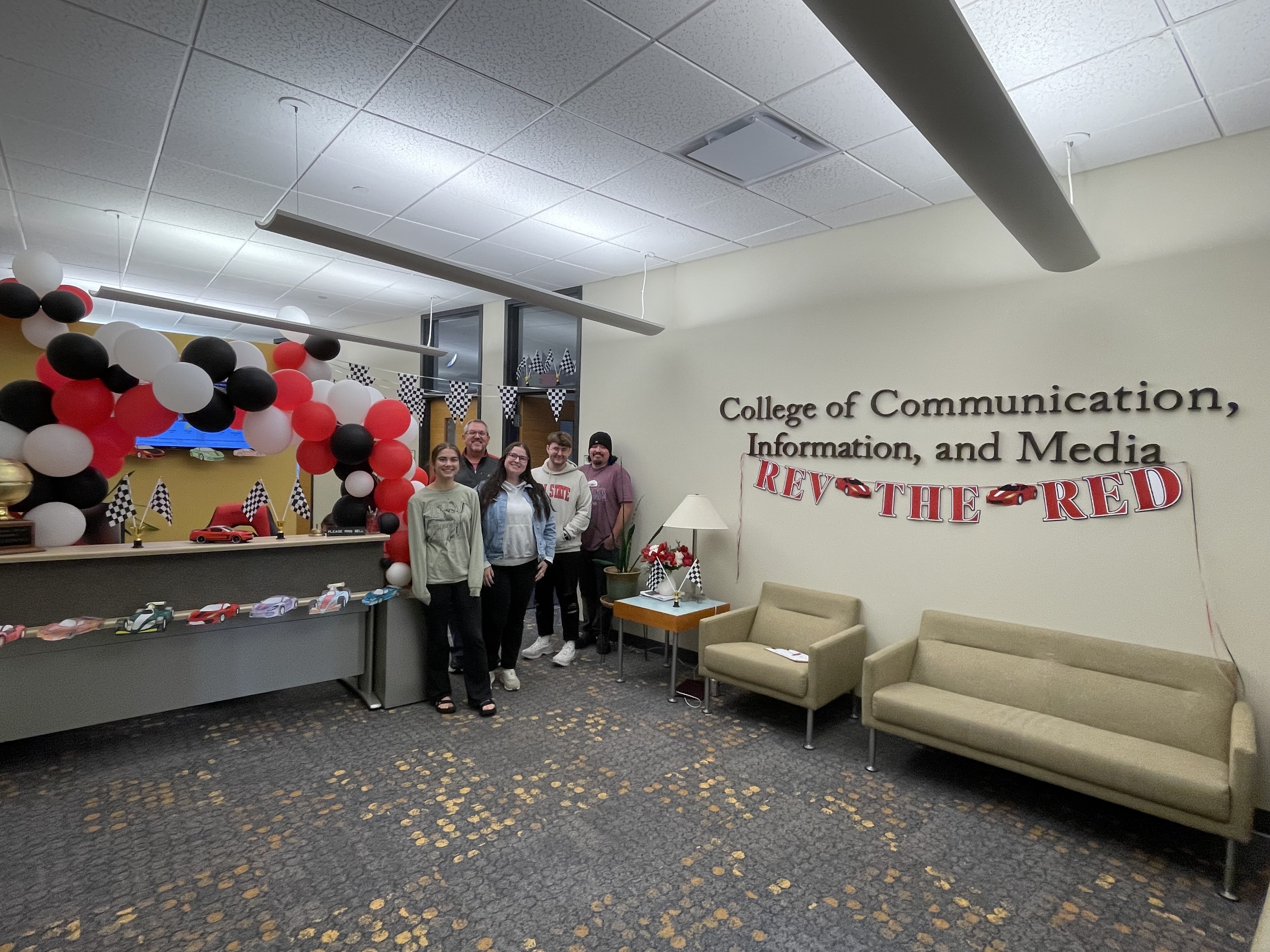 Group of People in front of Desk and wall decorated Race Theme