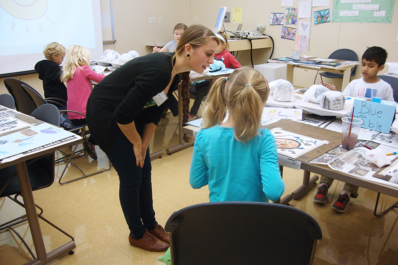 Art education classroom - teacher instructs the classroom of child painters