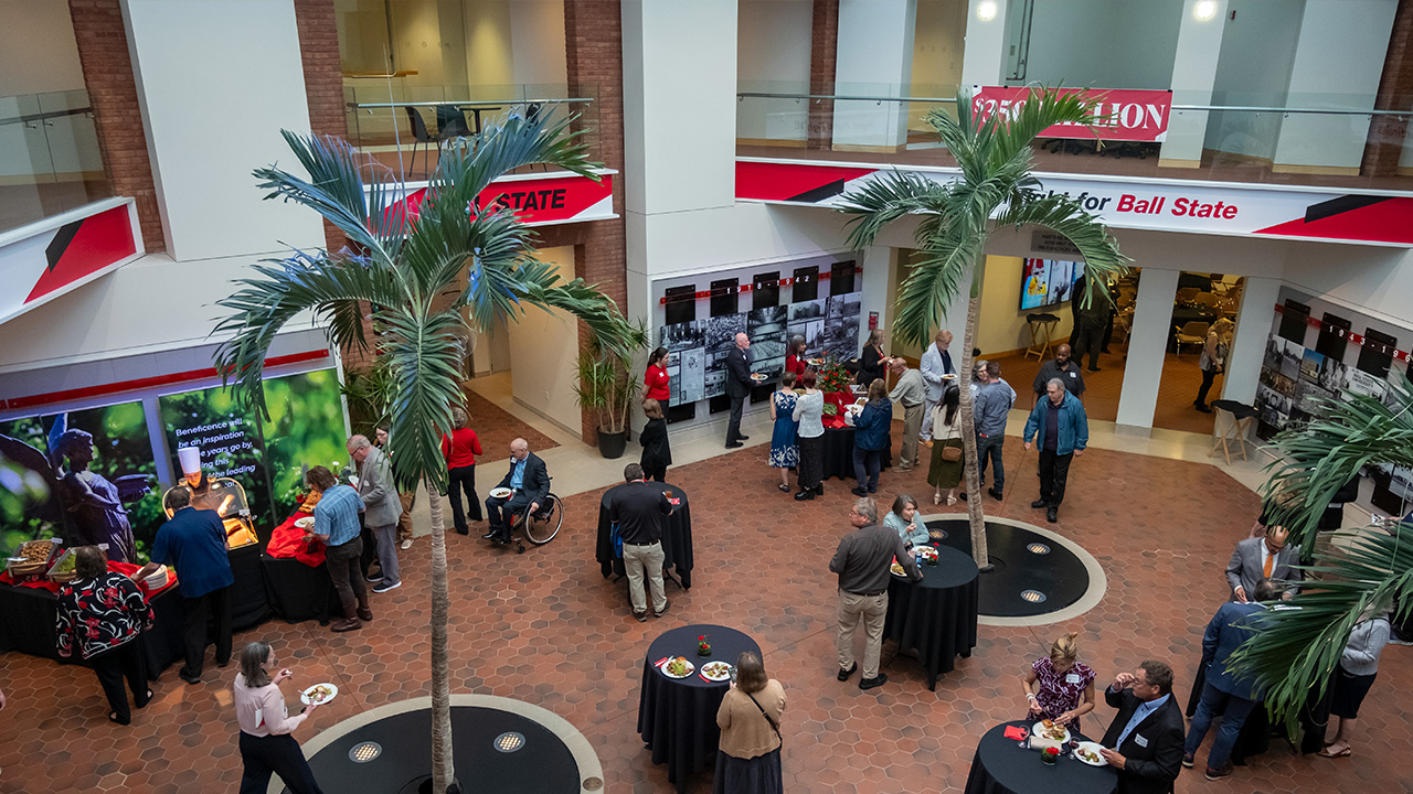 Large open area with palm trees and round standing tables with people