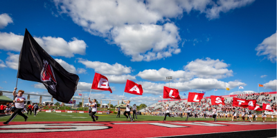 Cheerleaders running flags at football game