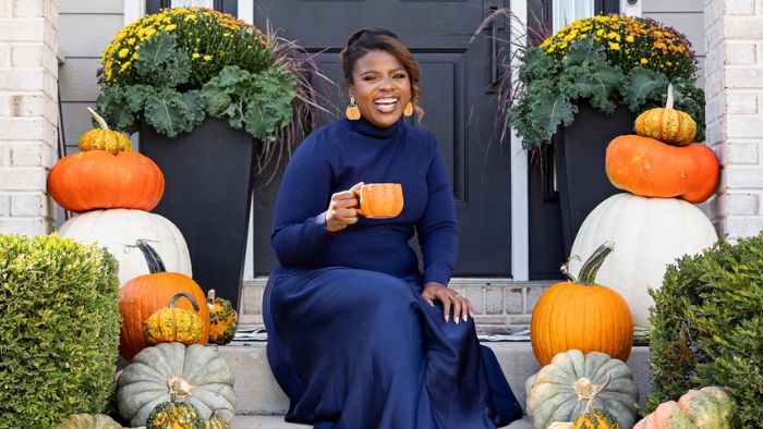 Female in dark blue dress on front porch decorated with fall decor