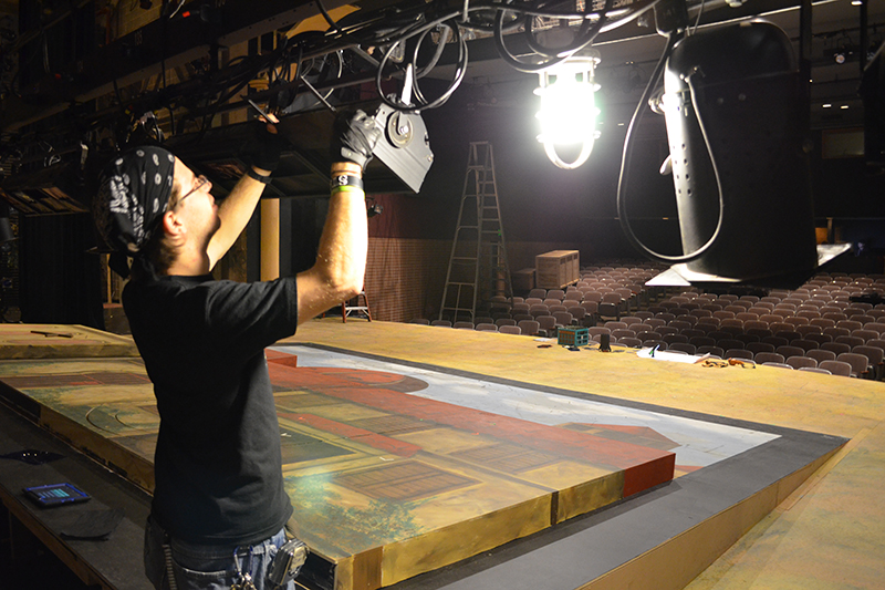 student fixing lighting in scene shop