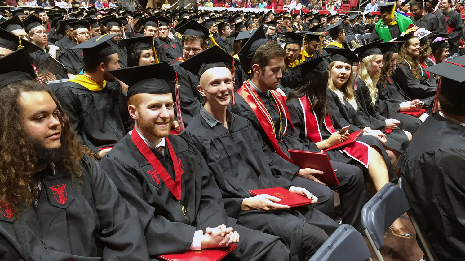 students at commencement ceremonies, wearing academic regalia