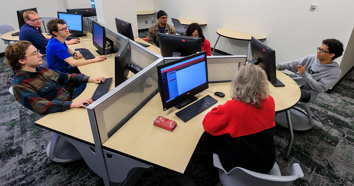 A group of students sitting at computers working together on a project