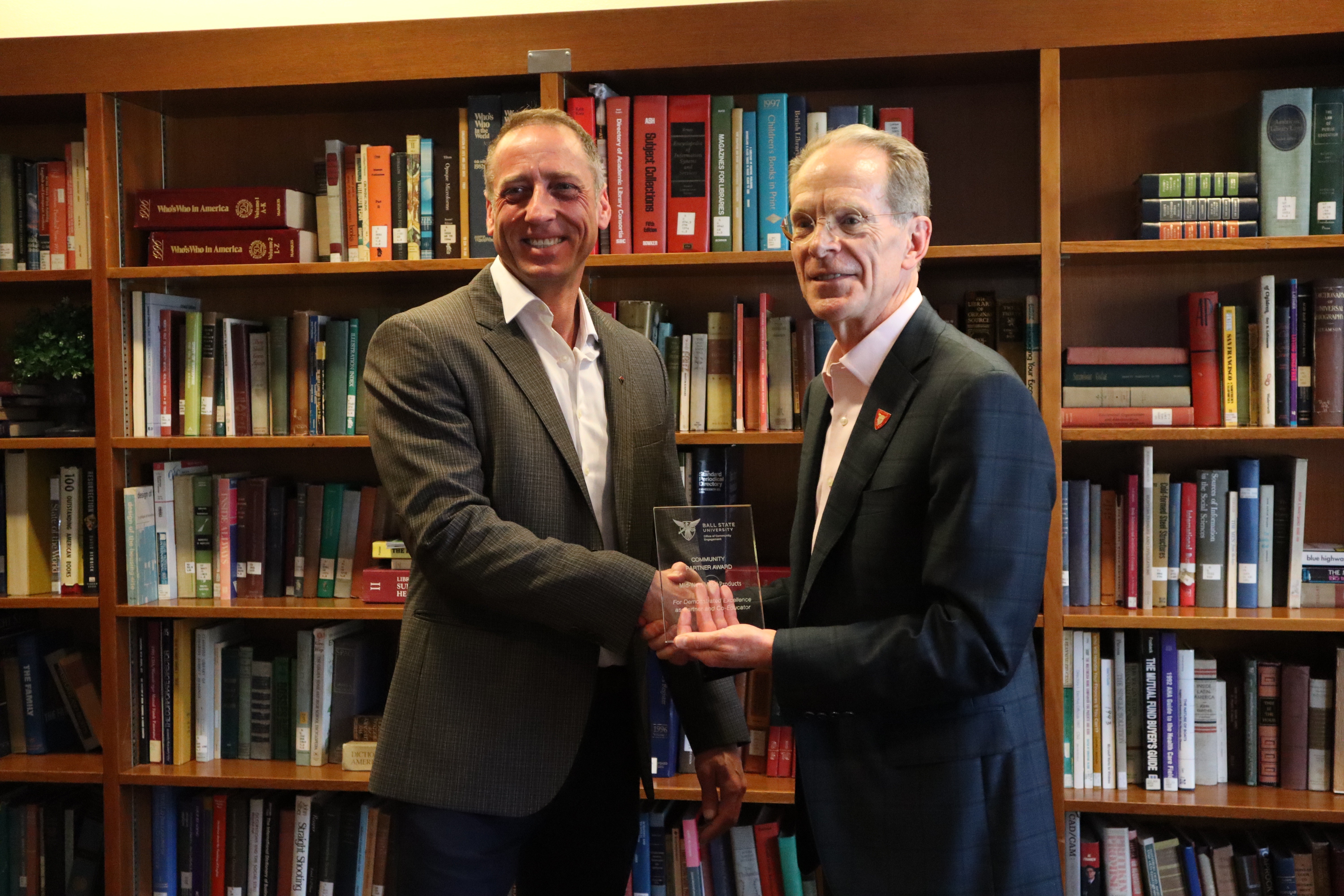 John Smith of Midwest Metal Products receives a 2025 Outstanding Community Partner Award from President Geoffrey Mearns.