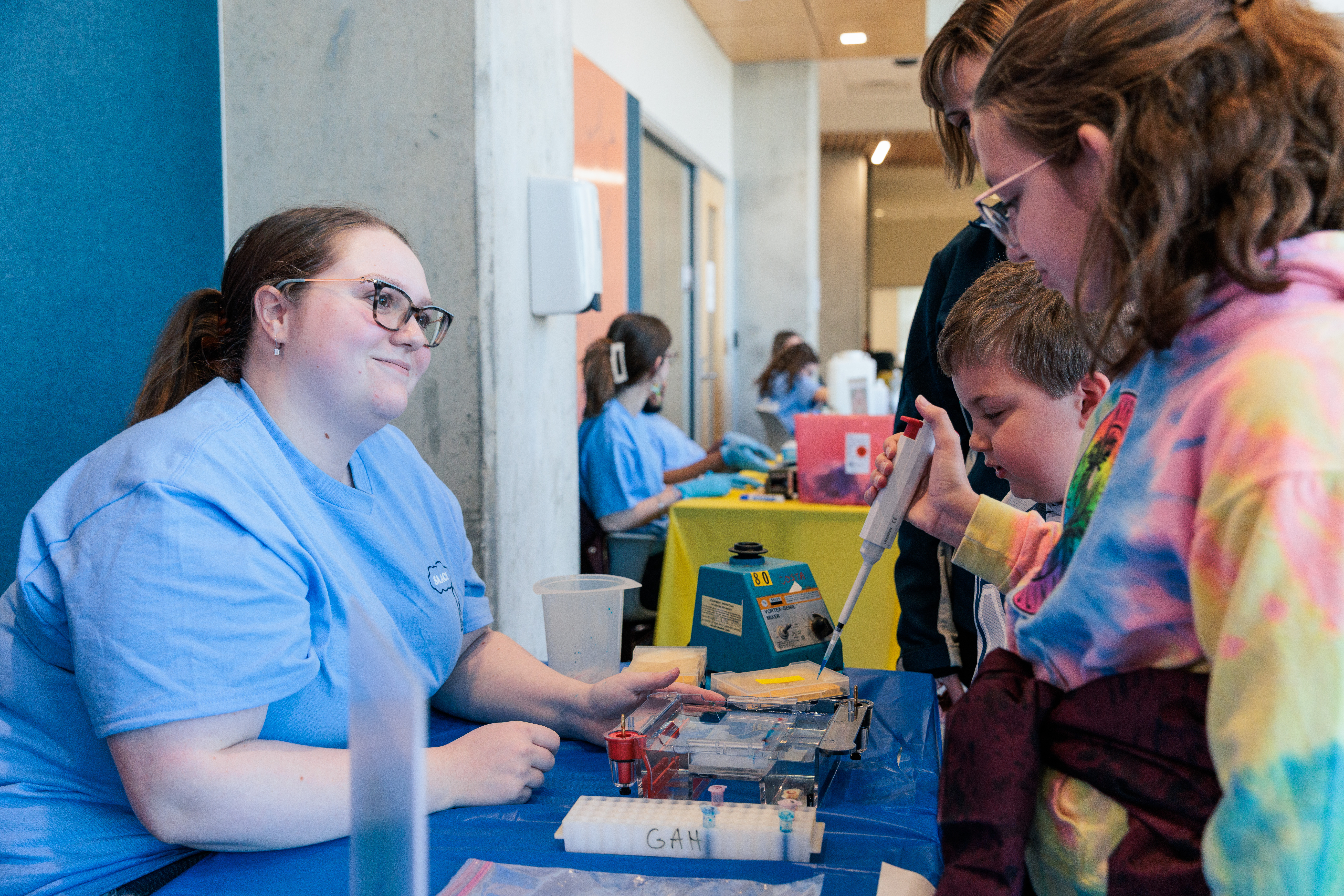 Elementary students use pipettes under college teaching student supervision
