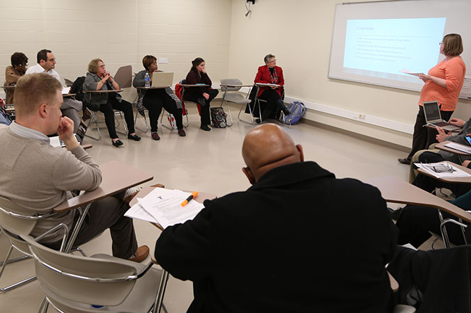 A group of adults sitting in a classroom while a professor lectures.