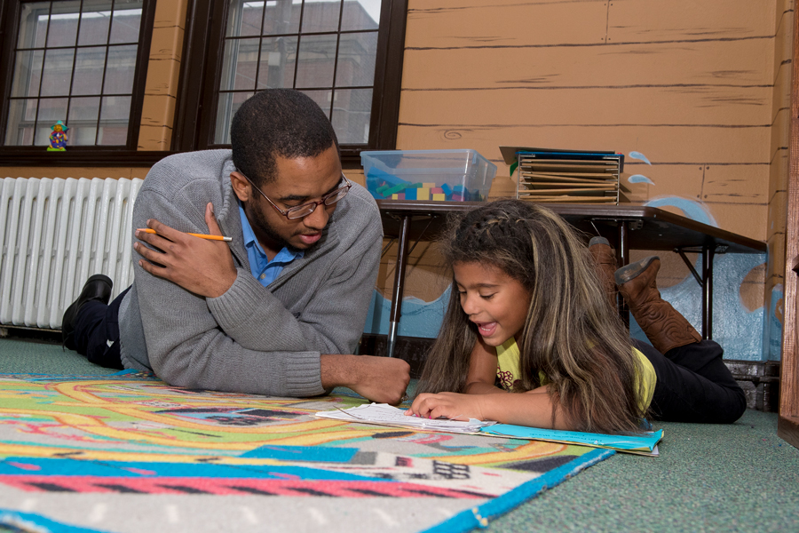 male student reading with a young girl in a classroom