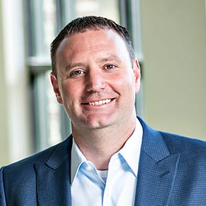 Headshot of a smiling man in a suit and tie 
