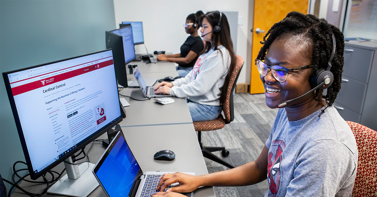 Ball State students wearing headsets work at computers in a call center assisting prospective students 