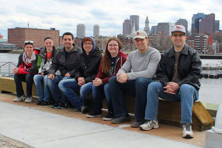 group of people posing for photo in front of a river and city skyline