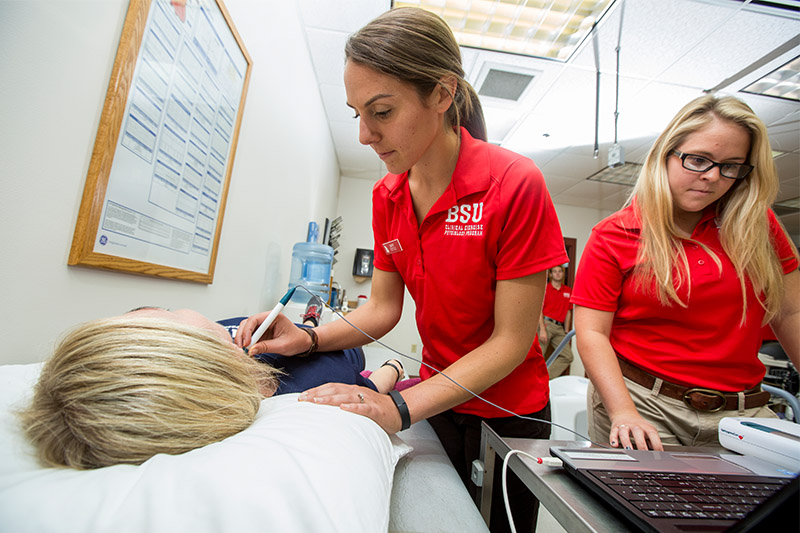 Graduate students examining a person in the Human Performance Lab.