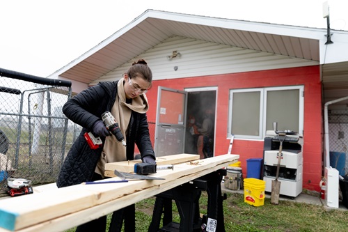 A student screws lumber together for a door frame