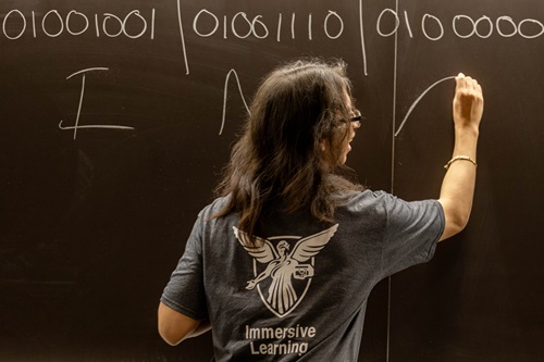 A student explains binary code on a blackboard