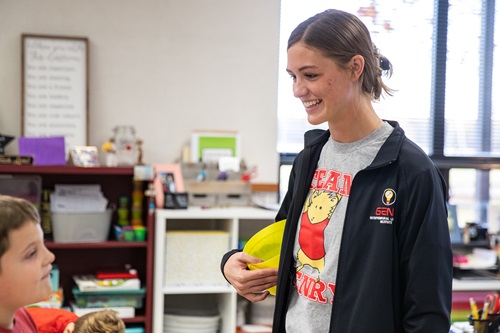 A college students smiles at a younger student