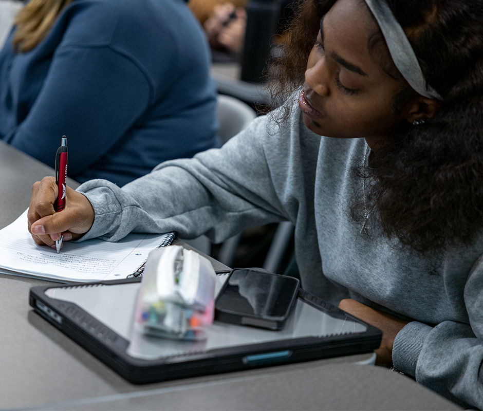 Student at desk writing in a notebook