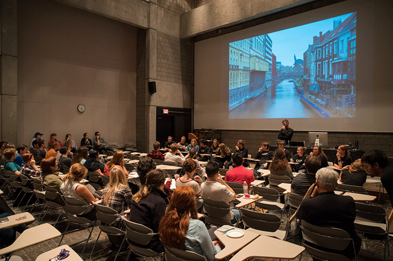 A large group of students watching a presentation in a lecture hall.