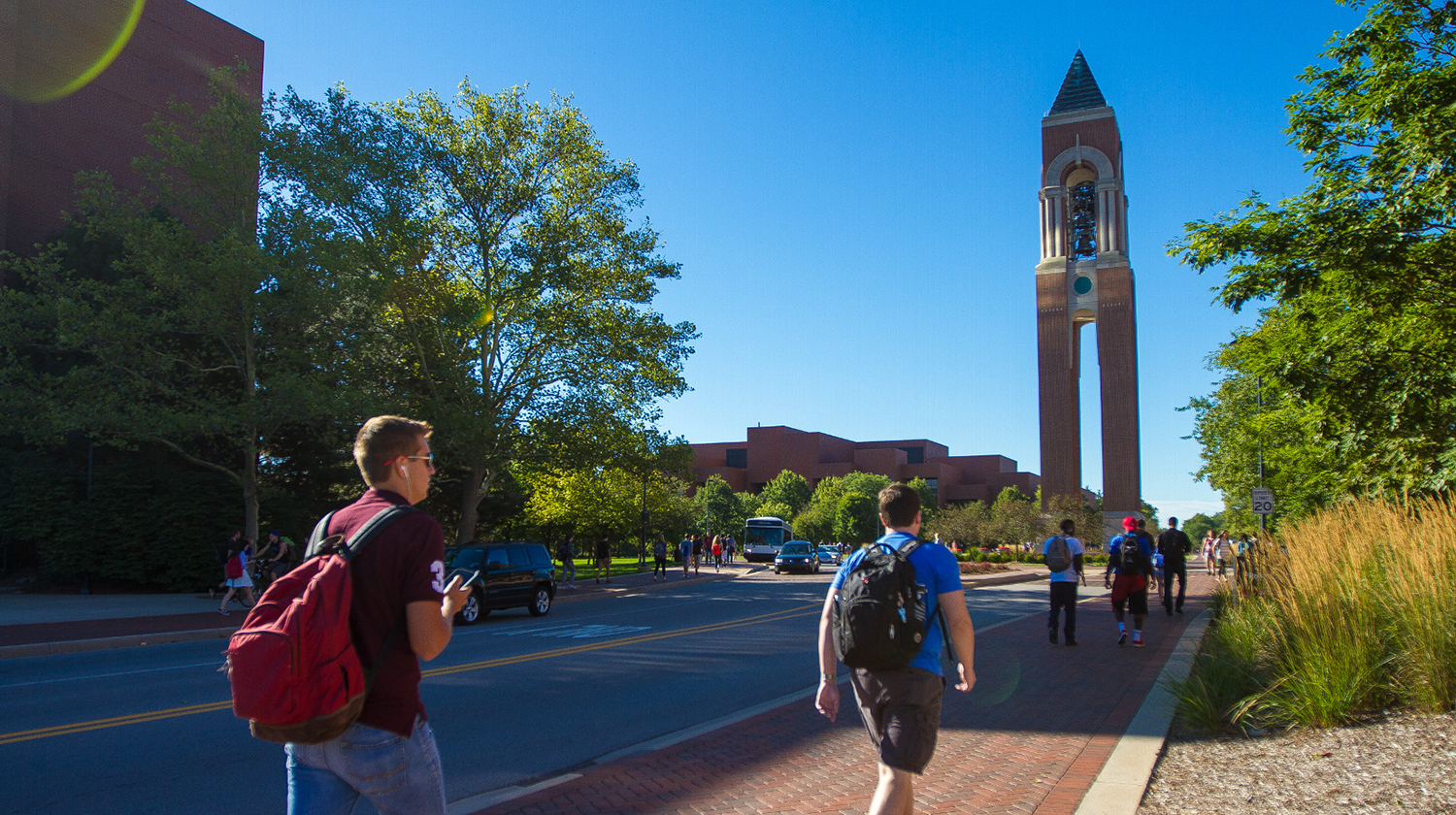 Students walking on campus near the bell tower.