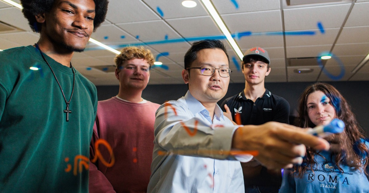 Math students watching a professor solve an equation on the board