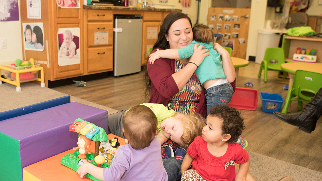 Early Childhood Education alumnus Michelle Thornburgh with several young children in an Early Head Start classroom