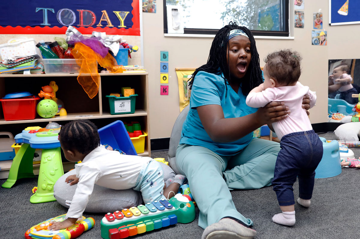 Soanirina DeJong holding a child in an early childhood classroom