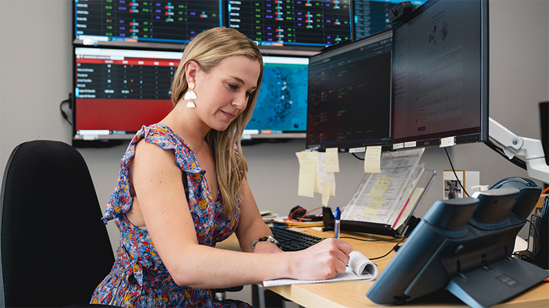 Woman writing on paper while seated at desk