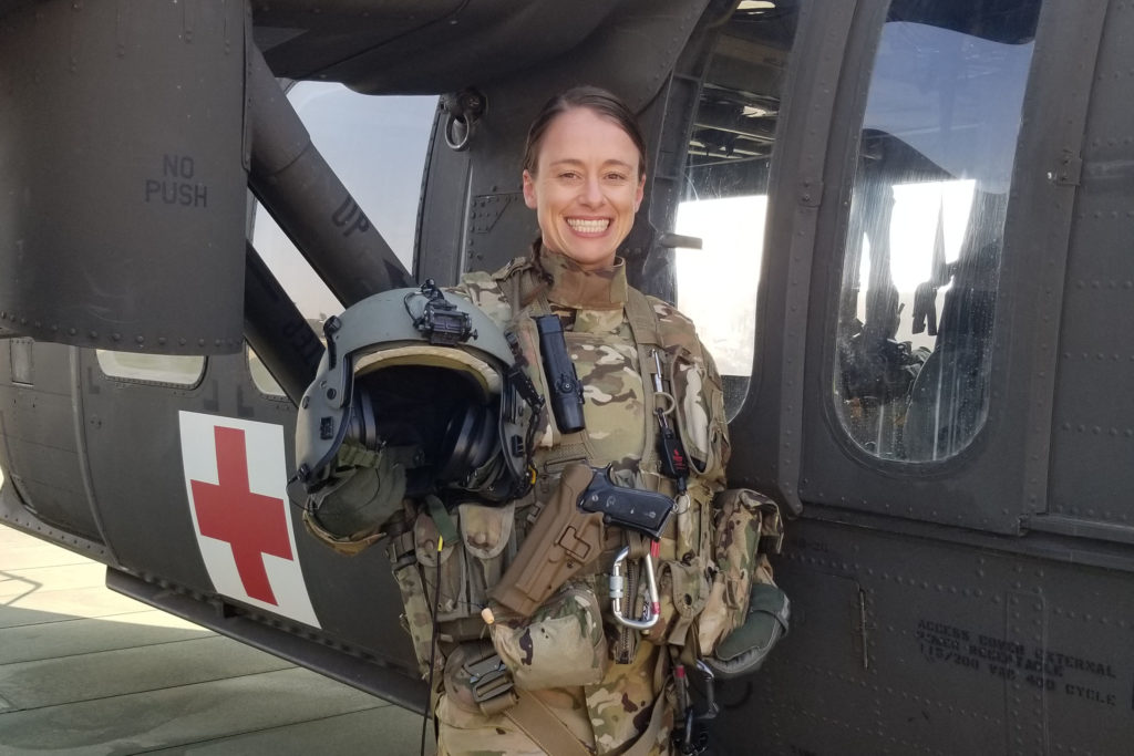A woman wearing military fatigues standing by a medical helicopter