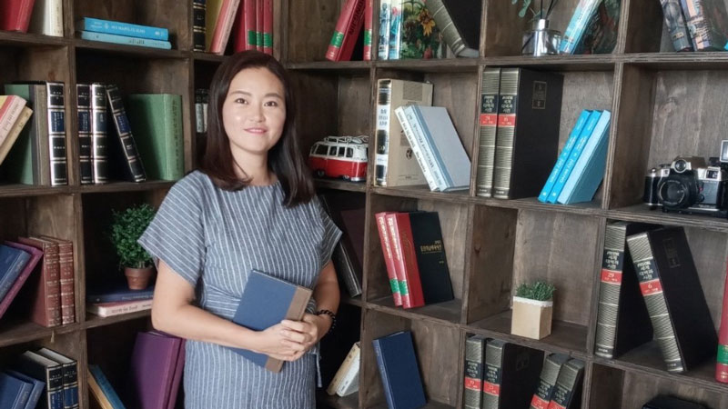 Hyeseok Lee holding a book in a library
