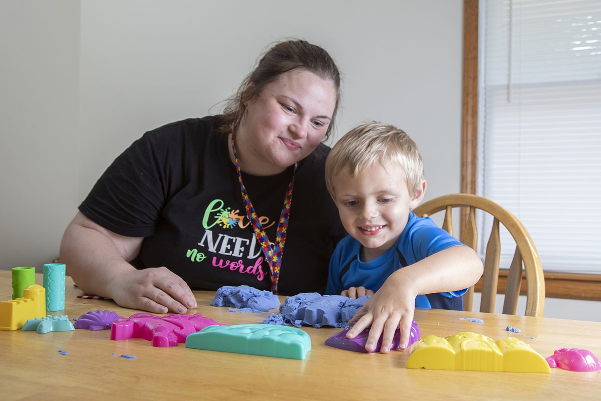 Woman watching a child play with dough at a table