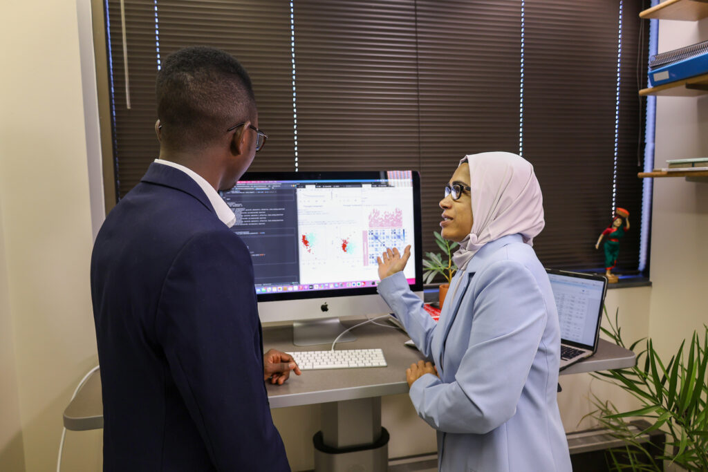 Data Analytics faculty Munni Begum talking with a student at a computer workstation