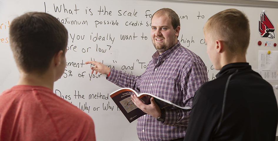 Nick Albers smiling and pointing to text on a whiteboard