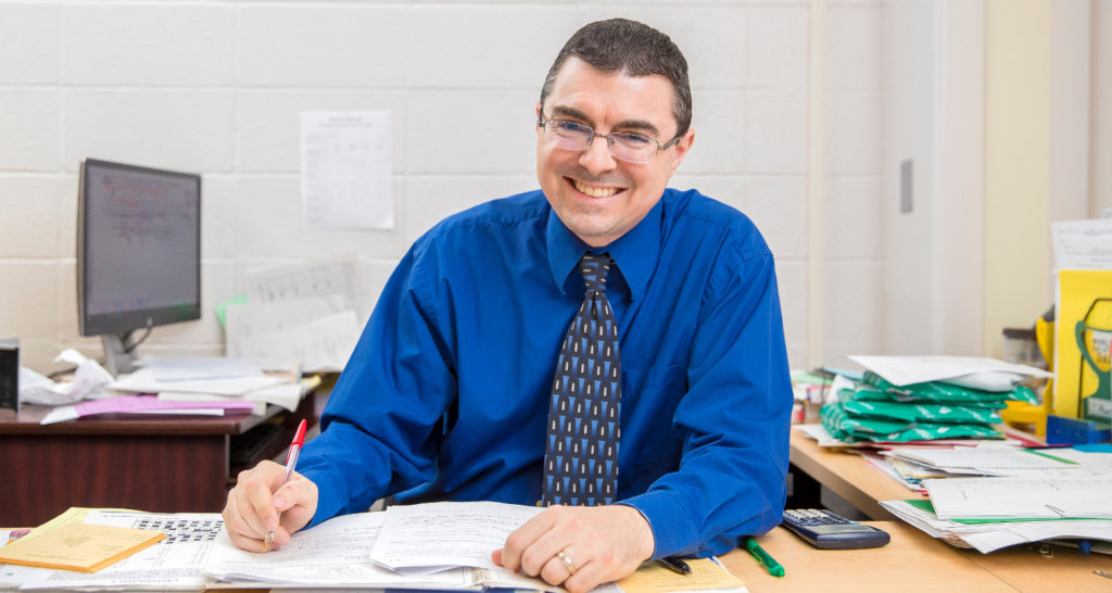 Man smiling while seated at a desk