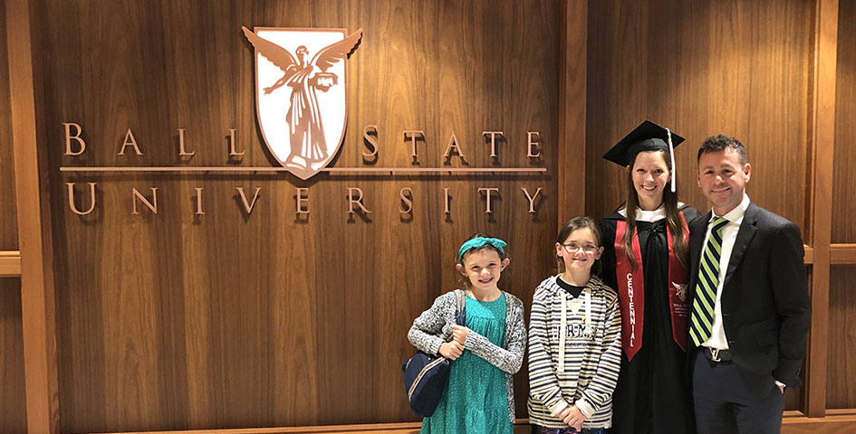 Lindsay posing with her family by a Ball State University sign