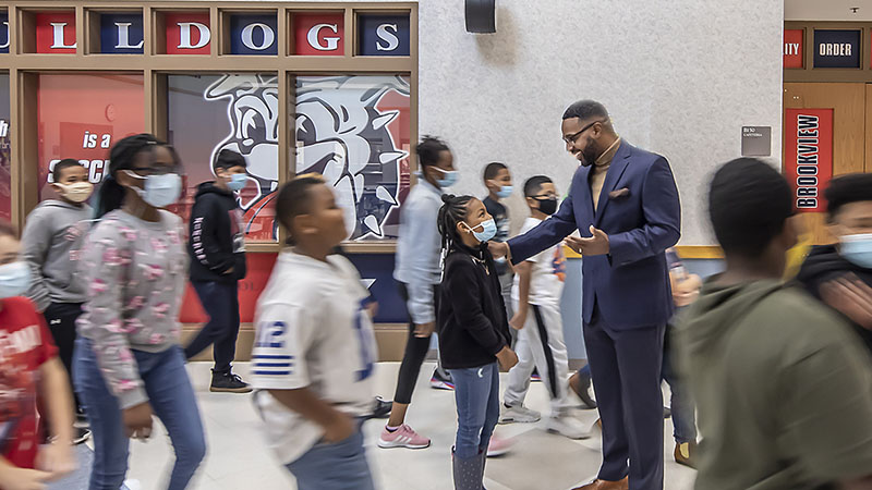 Jeremy Coleman speaks with a young student in a school hallway