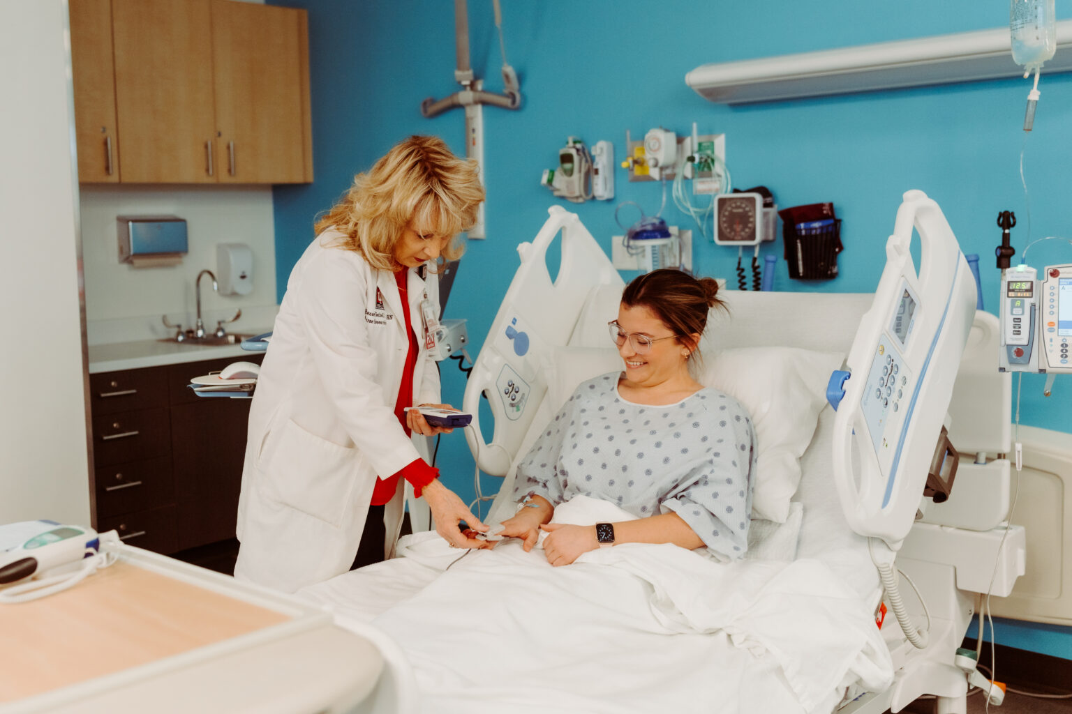 Woman in white lab coat with stethoscope talking to patient