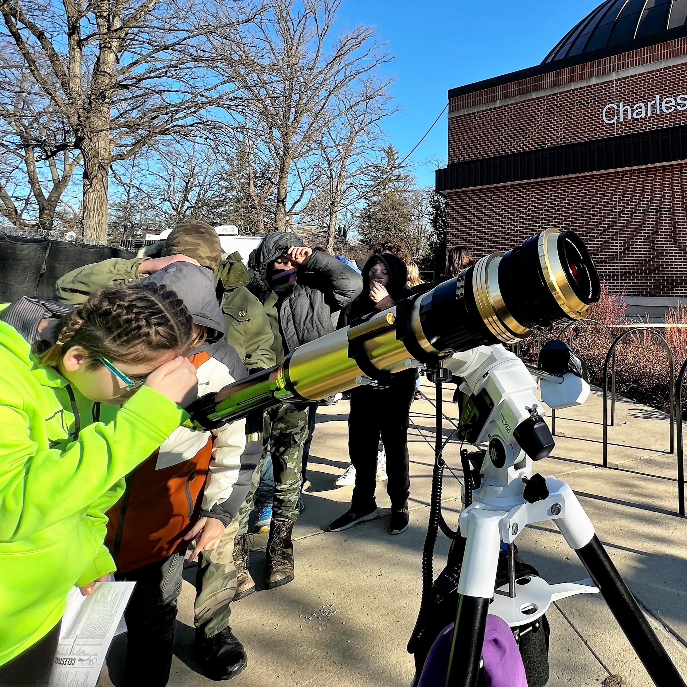 students looking through a solar telescope during the daytime