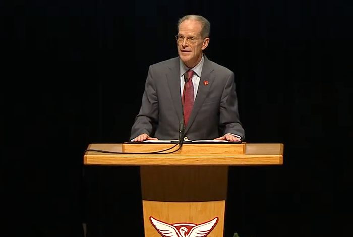 President Mearns behind podium with black background