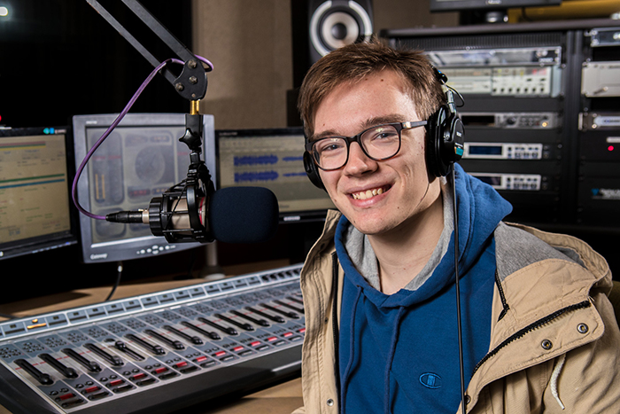A student smiles as he works in a recording studio.