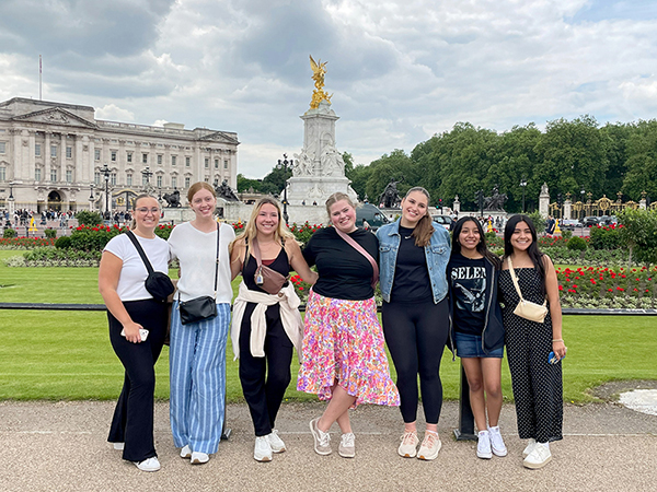 Students posing in front of statue in England