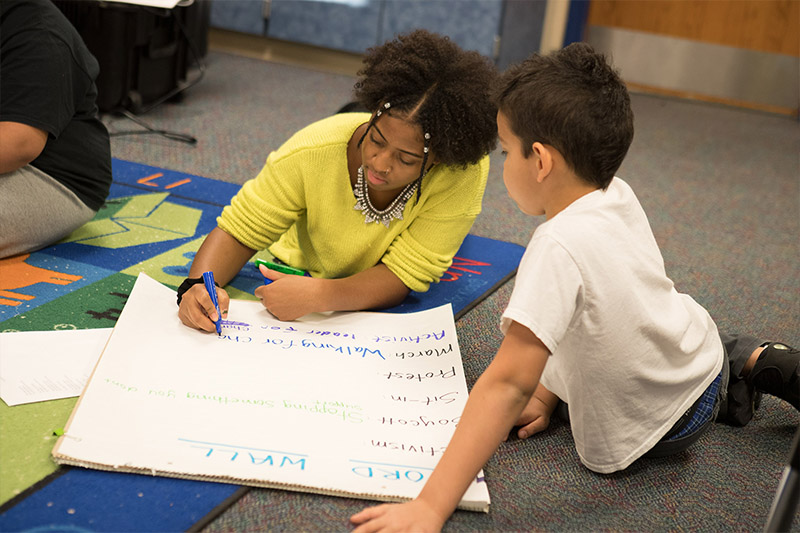 Ball State student works with child on the floor.