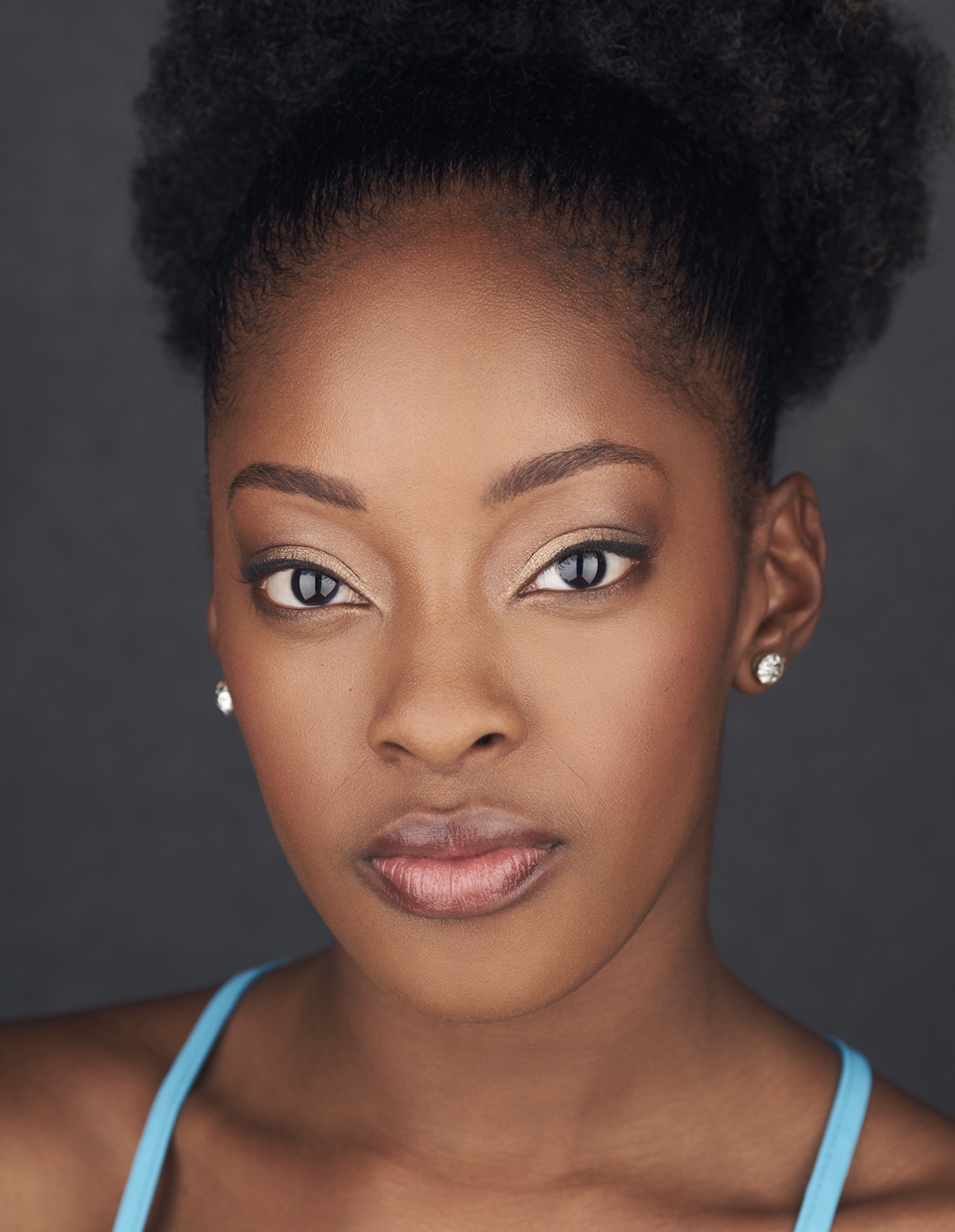 Photo of Kayla Davion. A Black/African American Female wearing a neon blue tank top with stud earings.