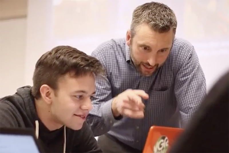 tyler smith instructs student at a computer