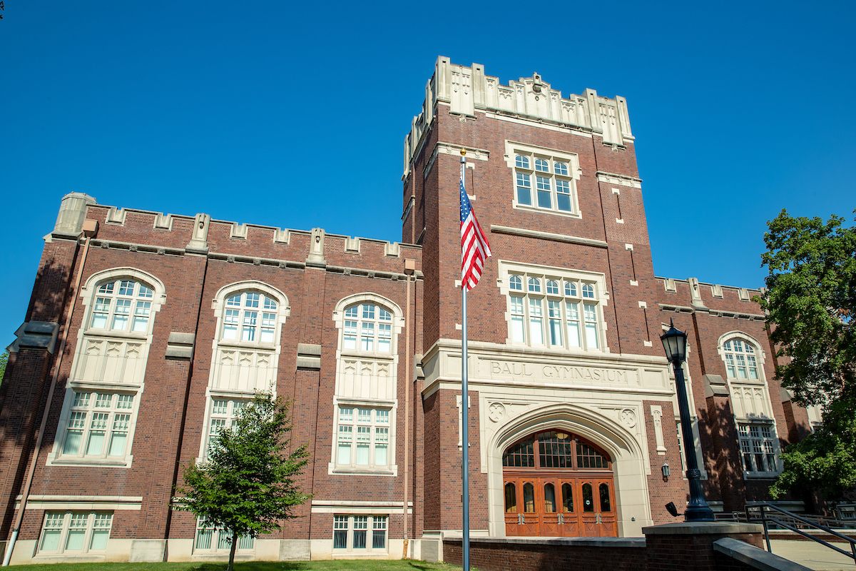 An image of Ball Gymnasium at Ball State University angled upward to see the blue sky behind the building. 