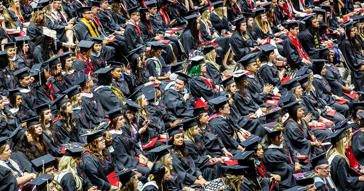Overhead shot of graduates dressed in black caps and gowns seated a graduation ceremony