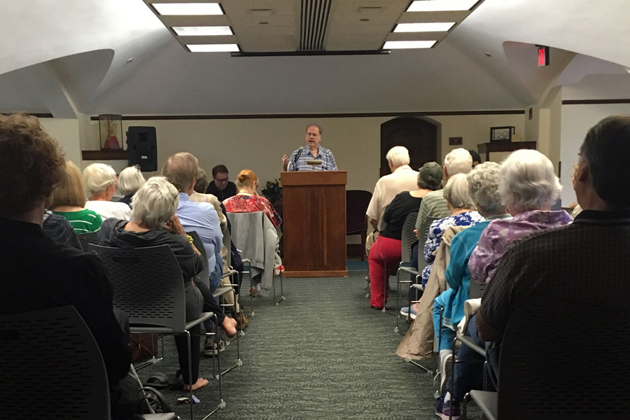 presenter at podium, speaking to room of people