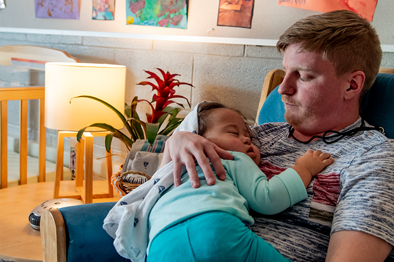 A student rocks a toddler at at the Mitchell Center