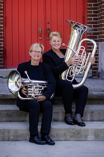 two women sitting on stairs and holding instruments